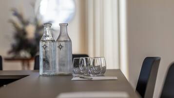 Una mesa de comedor con dos botellas de vidrio transparente y tres vasos vacíos.