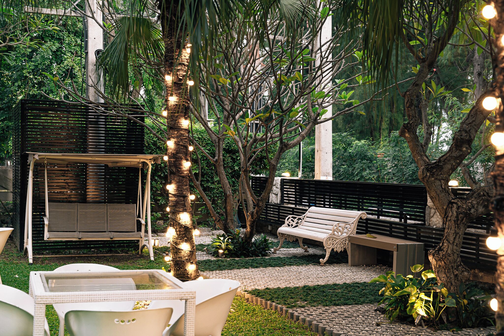 An outdoor seating area with a swing chair, a bench, and a table.