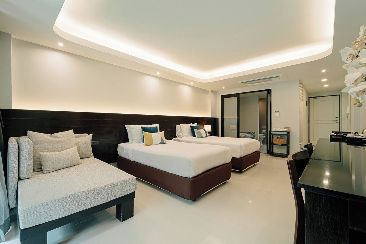 Une chambre d’hôtel moderne avec deux lits, un bureau et une salle de bain.