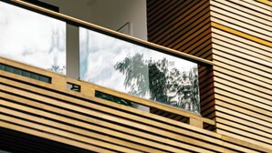 Een modern gebouw met een houten lamellen gevel en een glazen balkon.
