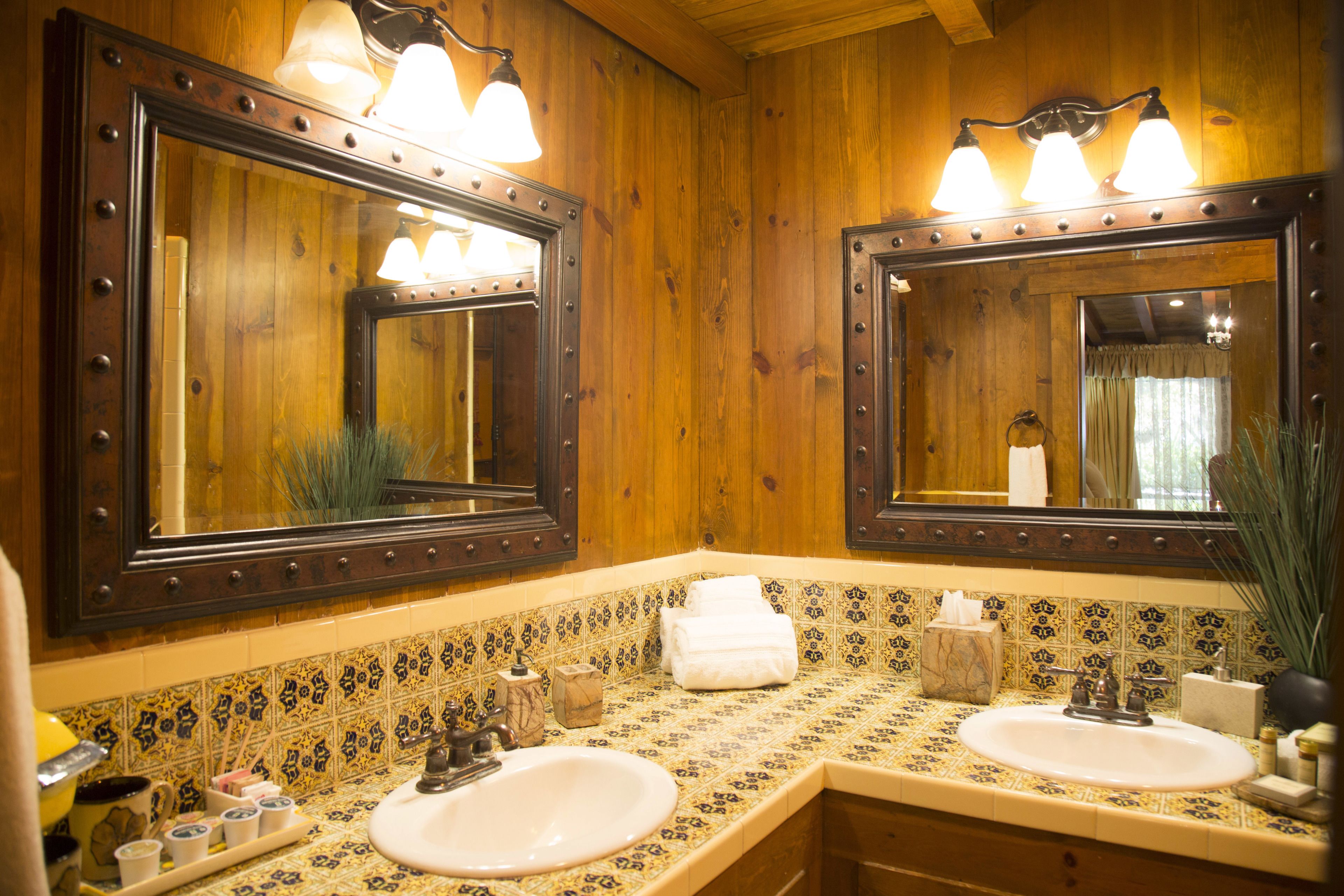 Ein Badezimmer mit Holzwänden, zwei Waschbecken und einem großen Spiegel mit Beleuchtung.