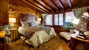Una habitación acogedora de madera con una cama grande, una mesita pequeña y una silla.