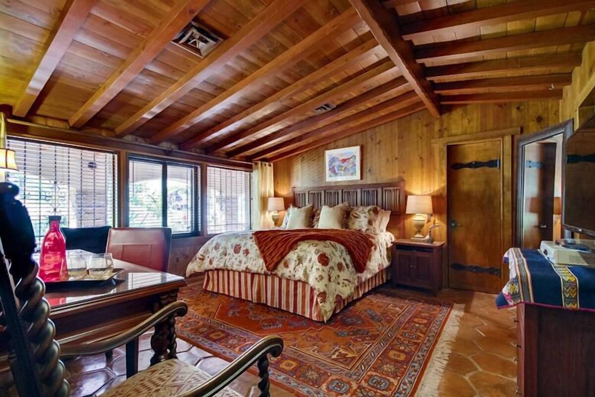 A wooden-floored bedroom with a bed, a desk, and a chair.