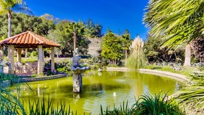 Un jardín con un pabellón, un estanque y diversas plantas.