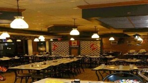 Un restaurante con varias mesas y sillas, lámparas colgantes y una pared con diseño.