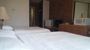 A hotel room with two beds, a wooden dresser, a television, and a microwave.