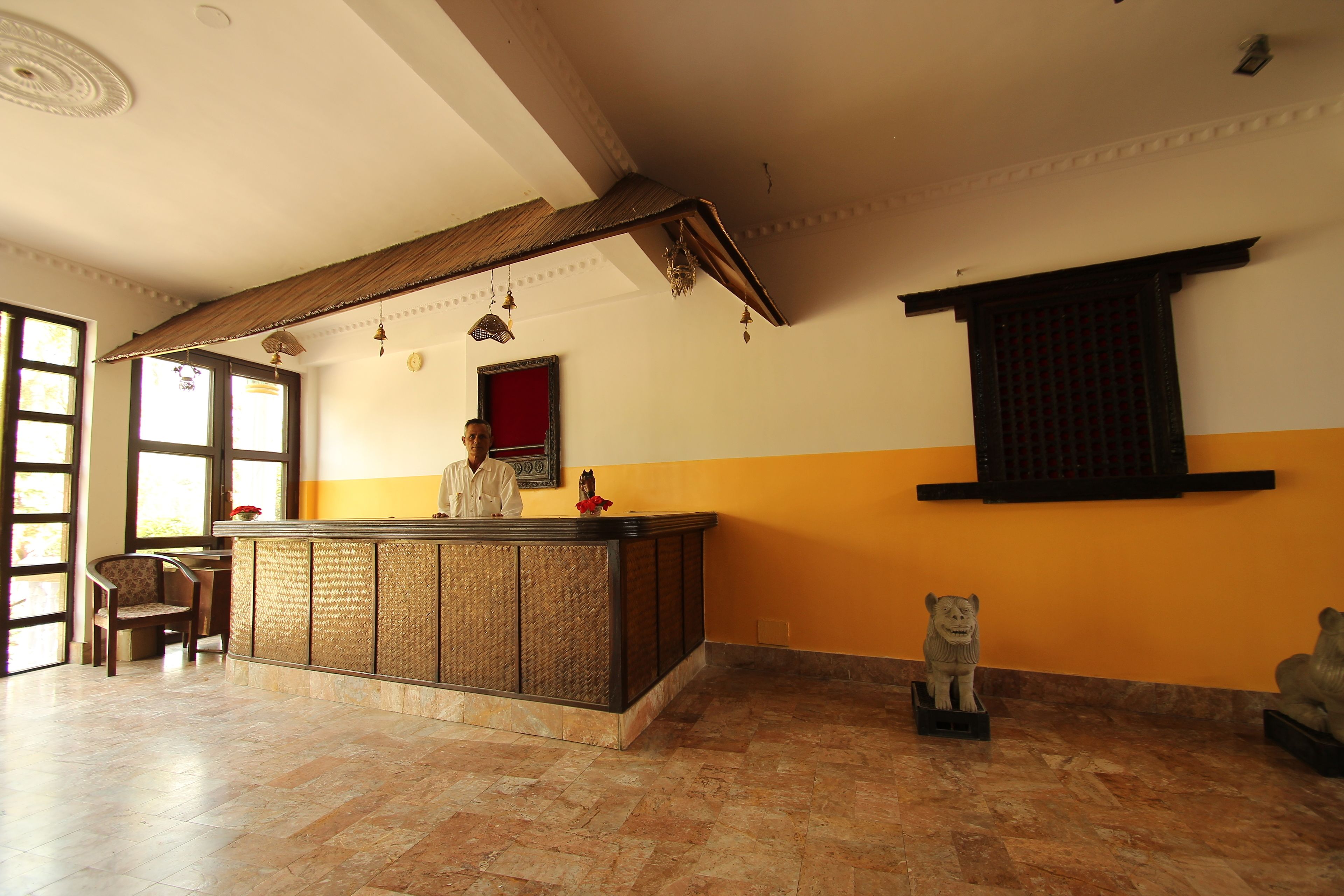 A reception area with a wooden reception desk, a chair, and a decorative wall hanging.