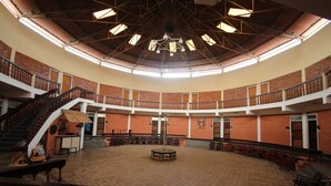 Un hallo espacioso con techo alto, múltiples escaleras y una zona circular central con mesas y sillas.