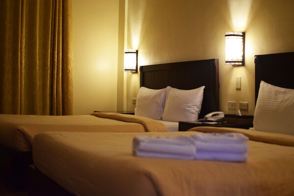 A hotel room with two beds, a nightstand with a phone, and wall-mounted lights. - Camayan Beach Resort (Morong)