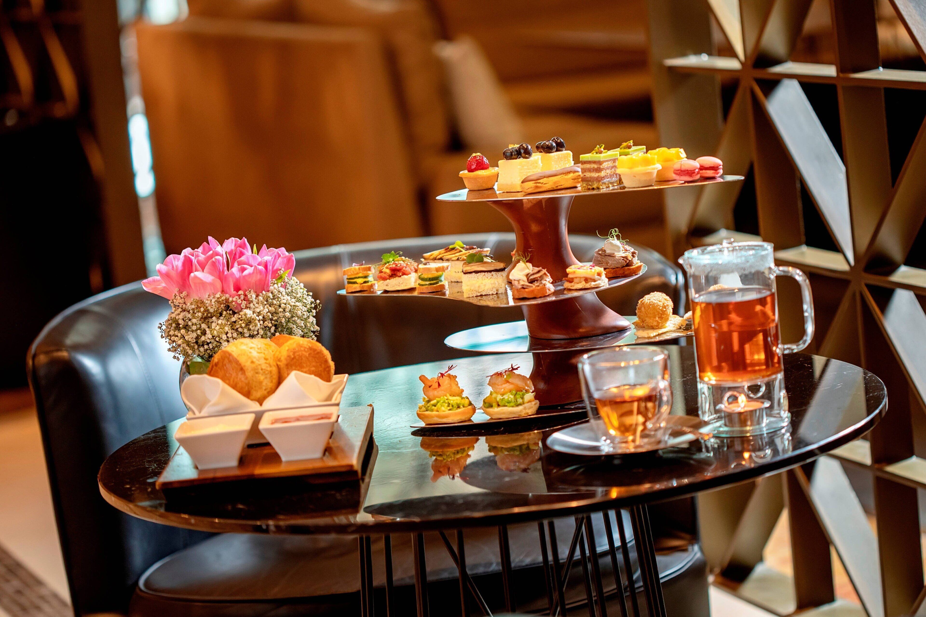 A table with a variety of food items and a pitcher of tea.