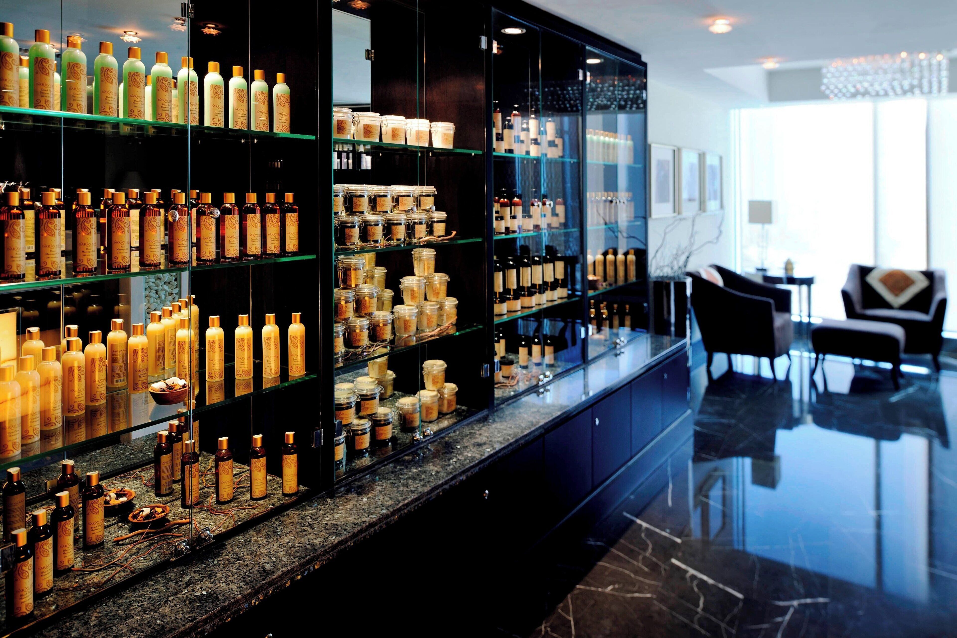 A bar area with shelves of bottles and jars, a marble countertop, and a seating area with chairs.