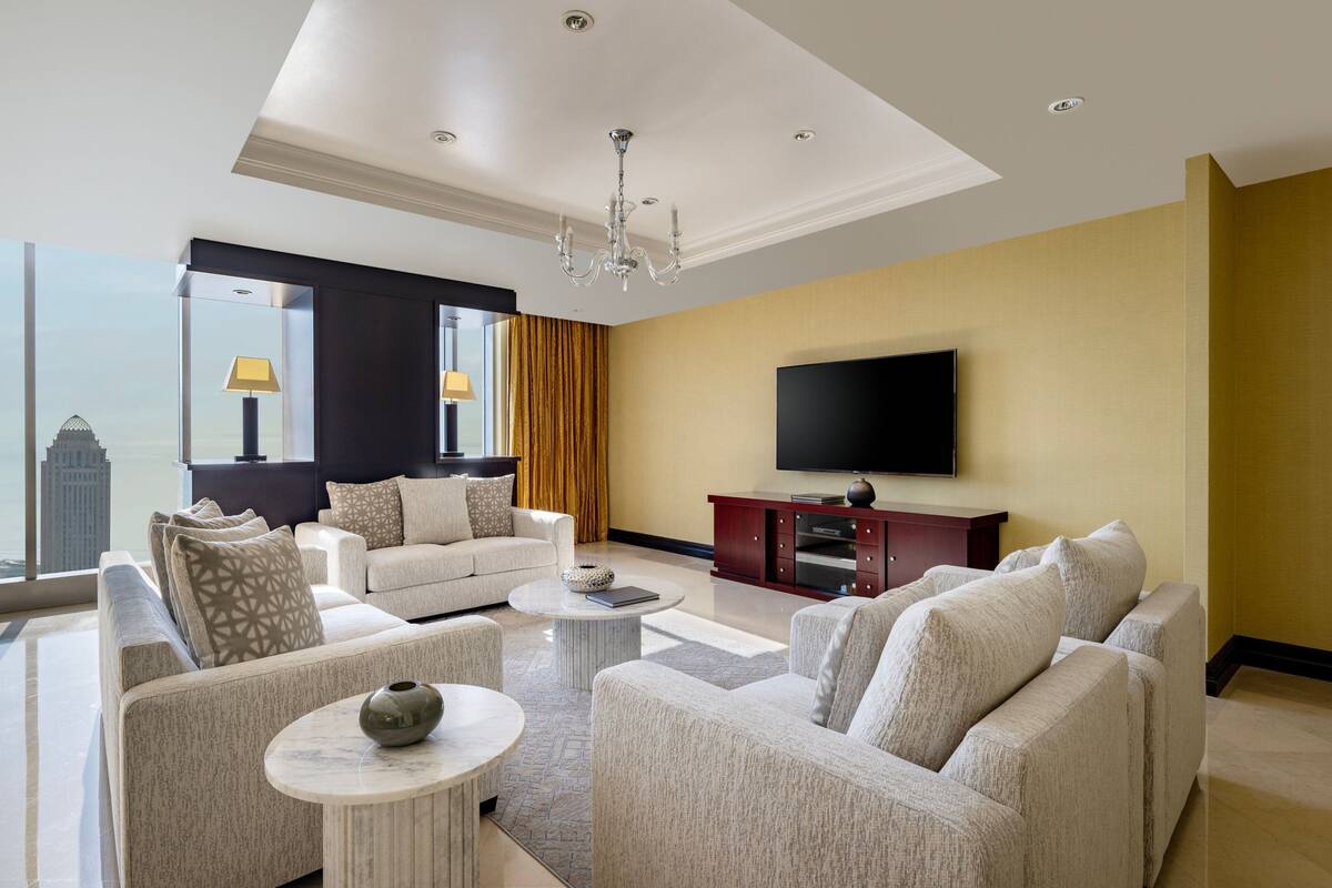 A modern living room with a sofa set, a coffee table, and a flat-screen TV mounted on the wall.