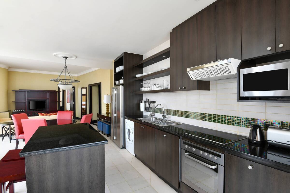 A modern kitchen with dark wood cabinets, stainless steel appliances, and a central island.
