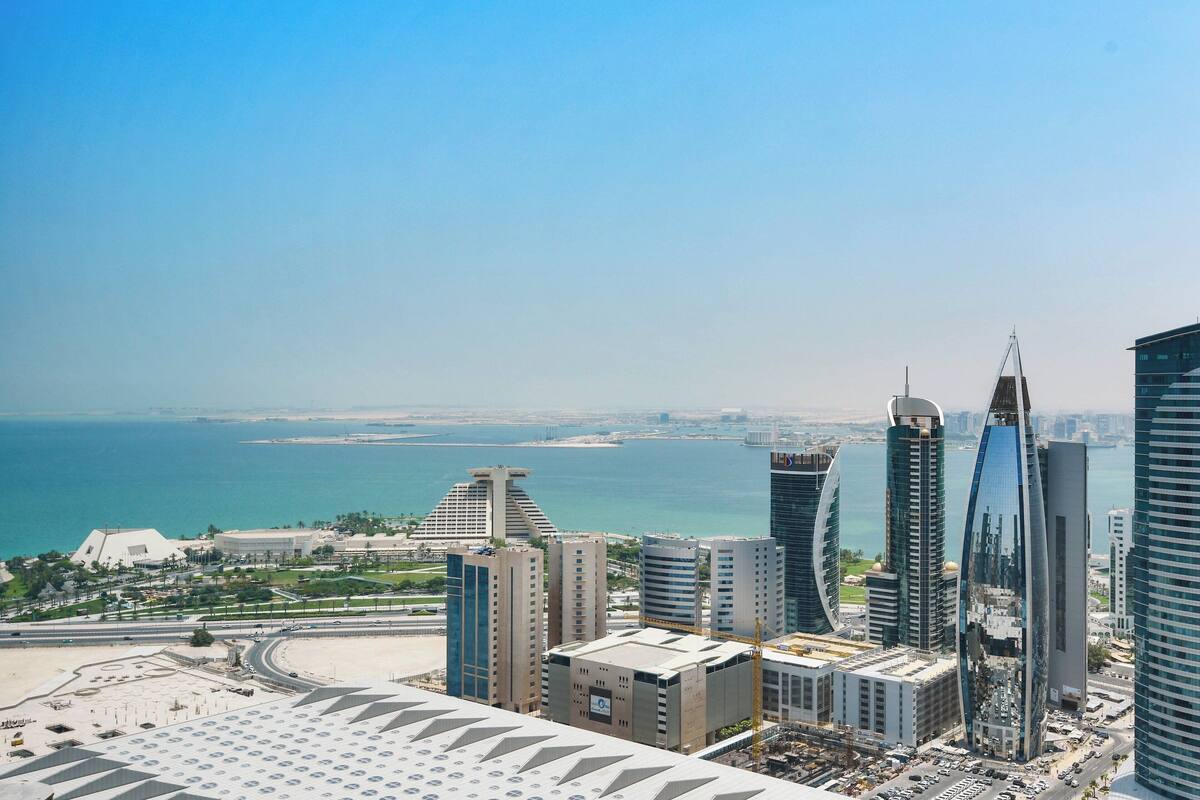 A cityscape with modern buildings, a waterfront, and a clear sky.