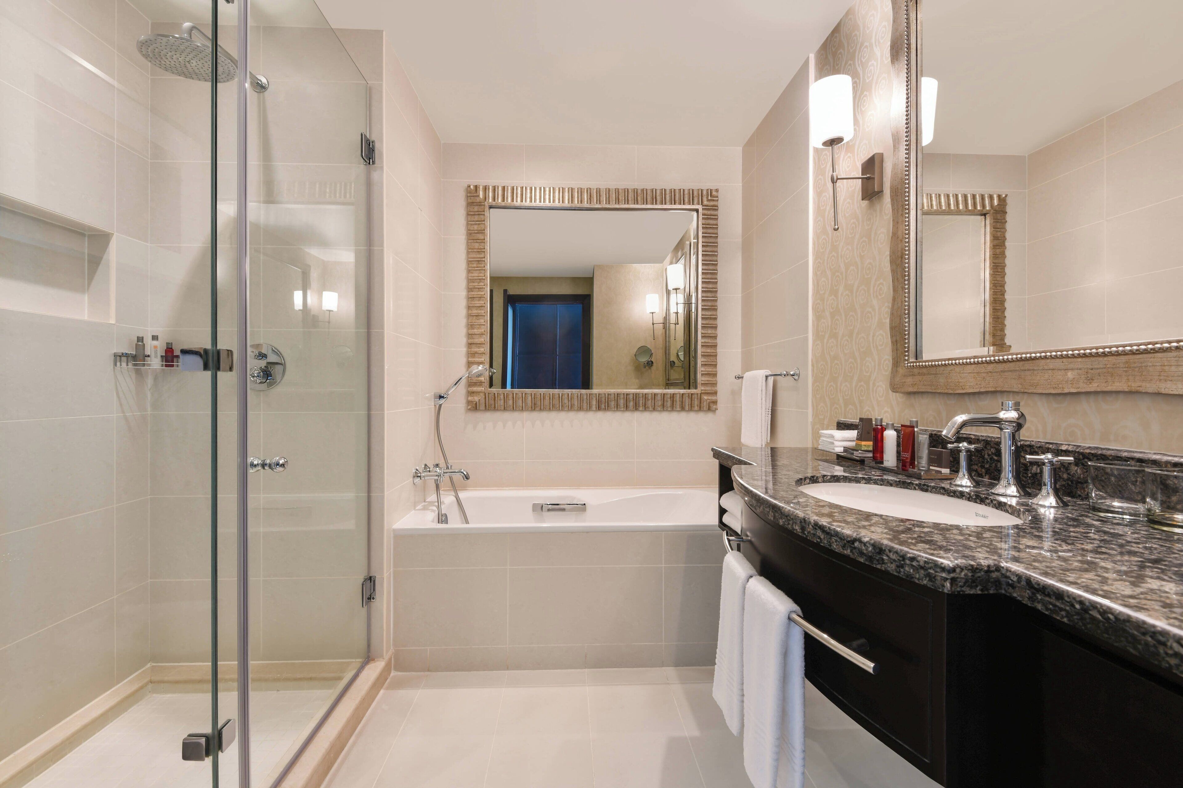 A modern bathroom with a glass-enclosed shower, a freestanding bathtub, and a vanity with a sink and mirror.
