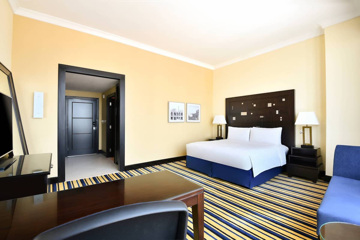 A hotel room with a bed, bedside tables, a desk, and a chair.