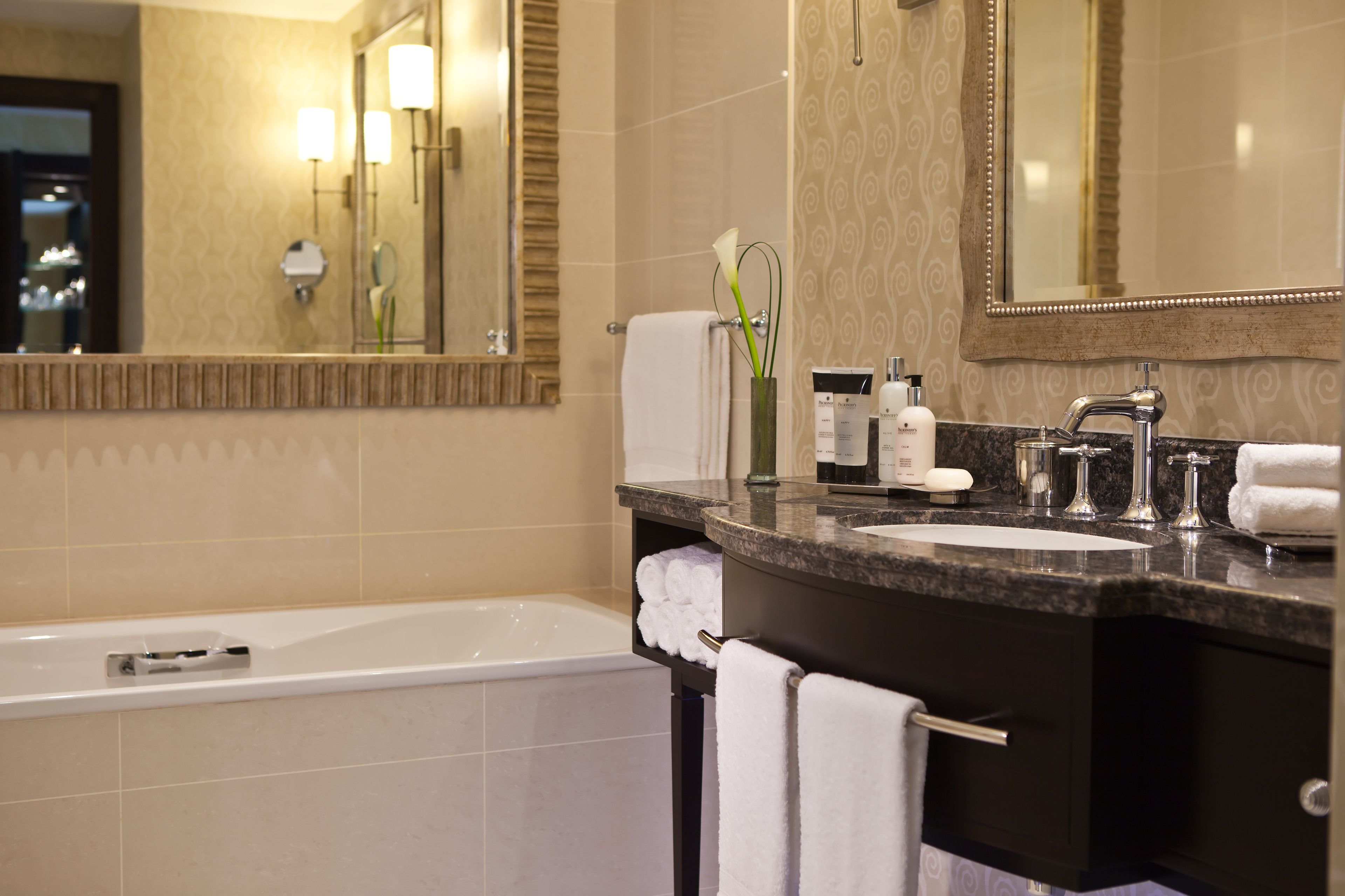 Un baño moderno con una bañera, un lavabo con tocador y un espejo grande.