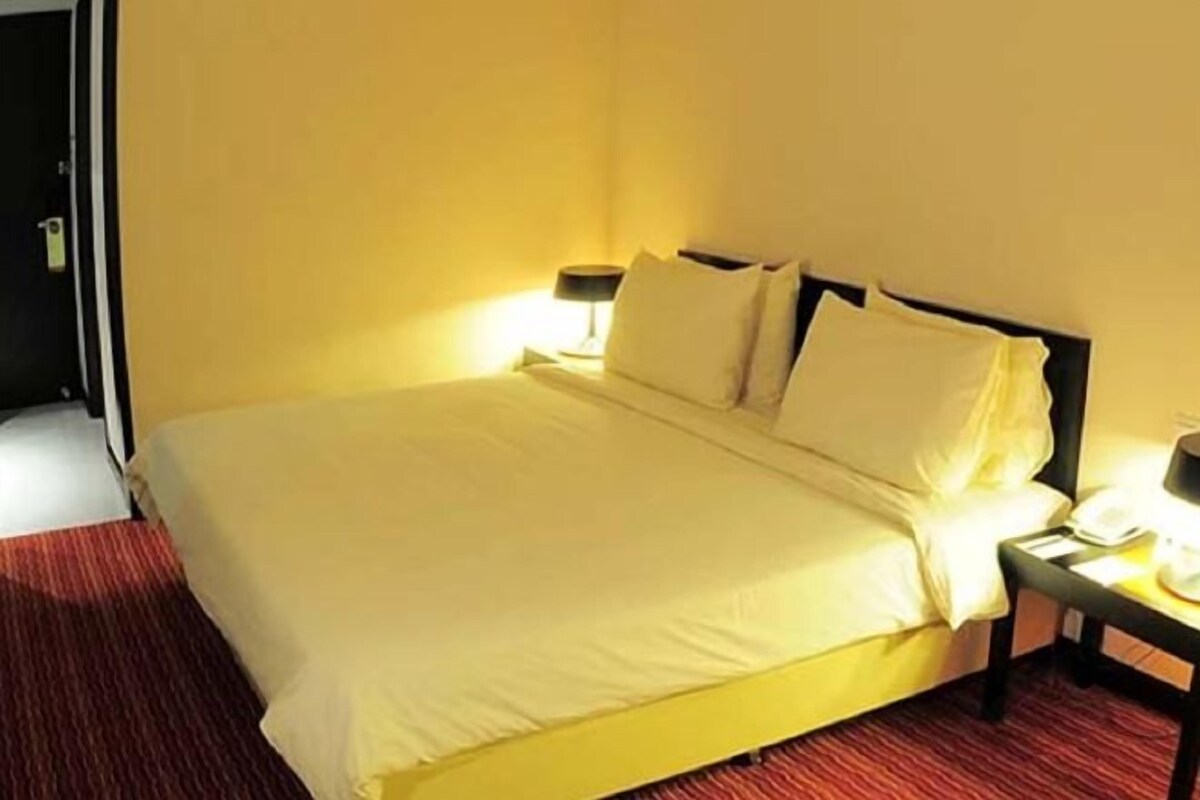 Une chambre d’hôtel avec un lit, une table de chevet et une lampe.