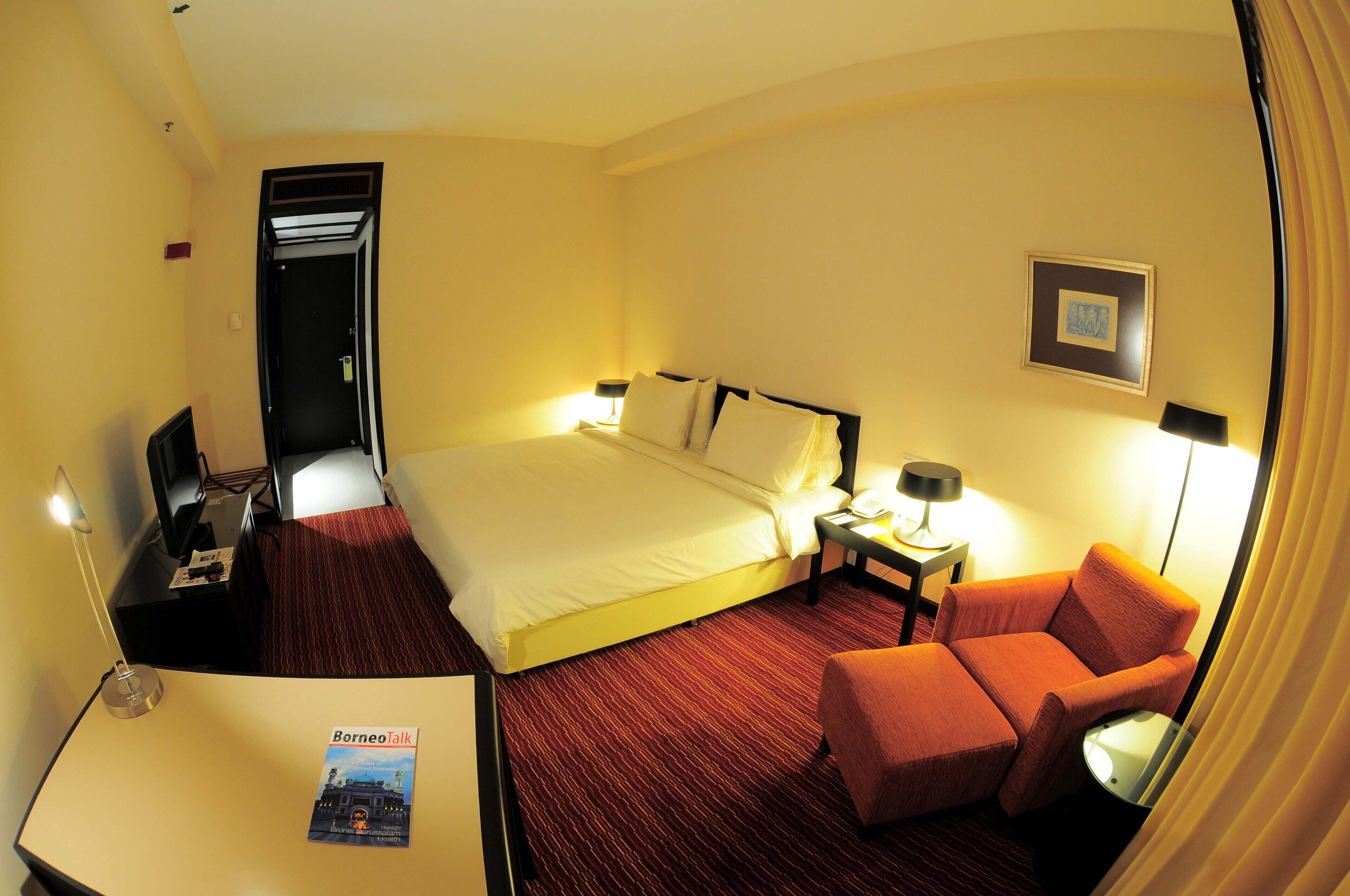 A hotel room with a bed, a desk, a chair, and a nightstand with lamps.