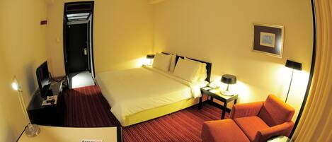 A hotel room with a bed, a desk, a chair, and a nightstand with lamps.