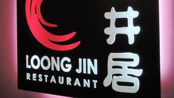 Ein Restaurantschild mit einem stilisierten roten und weißen Logo und chinesischen Schriftzeichen.