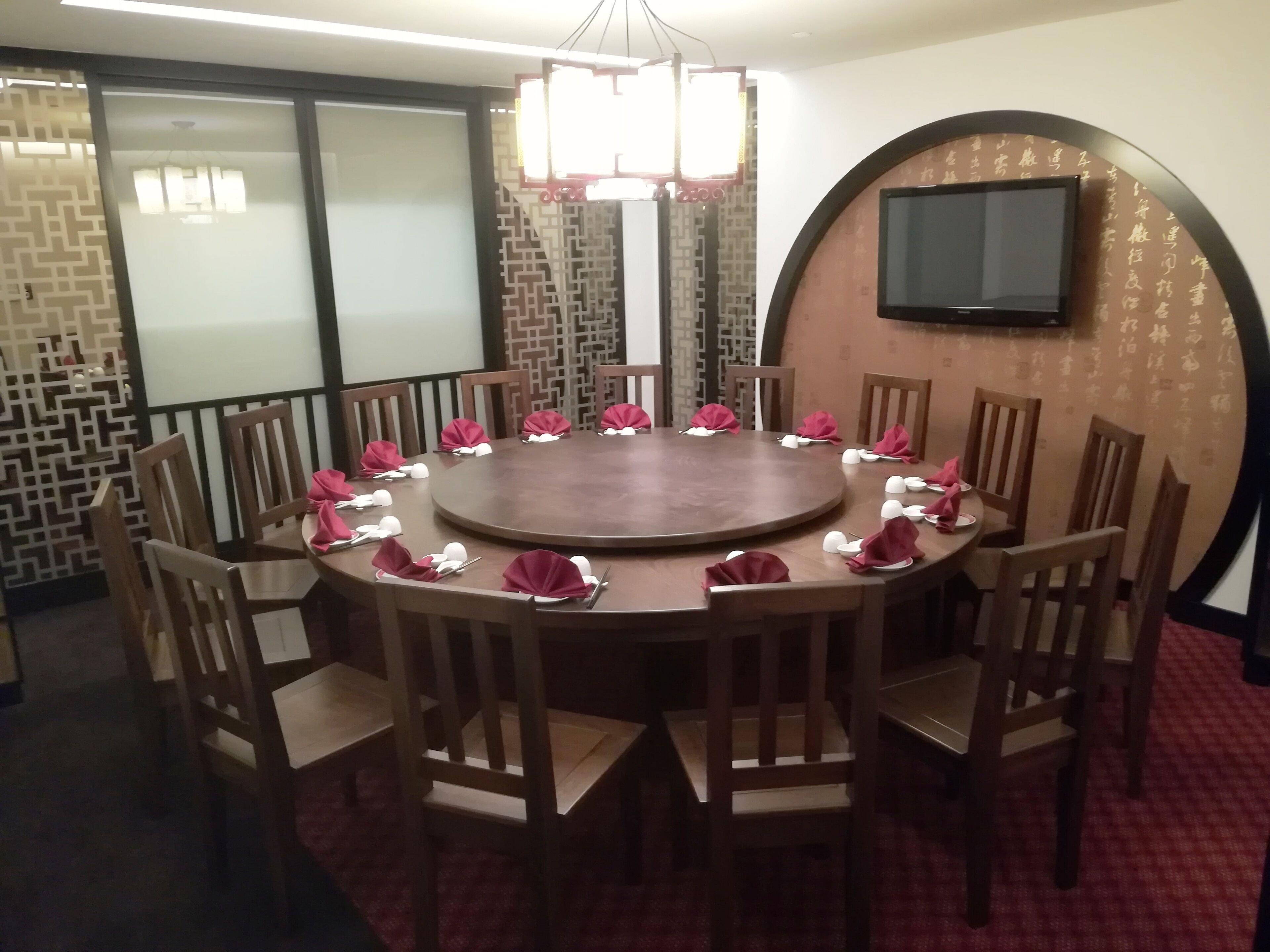 A conference room with a round table, wooden chairs, and a TV mounted on the wall.