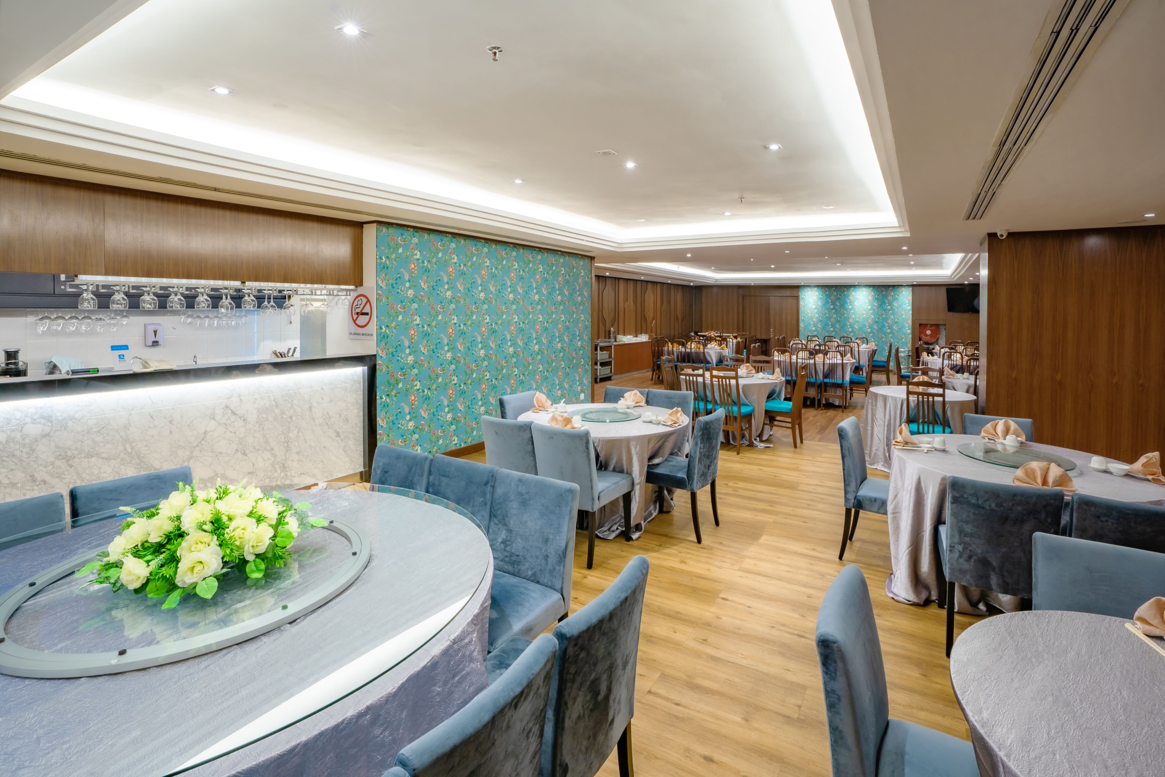 Un restaurante con mesas redondas, sillas azules y un centro de mesa floral.
