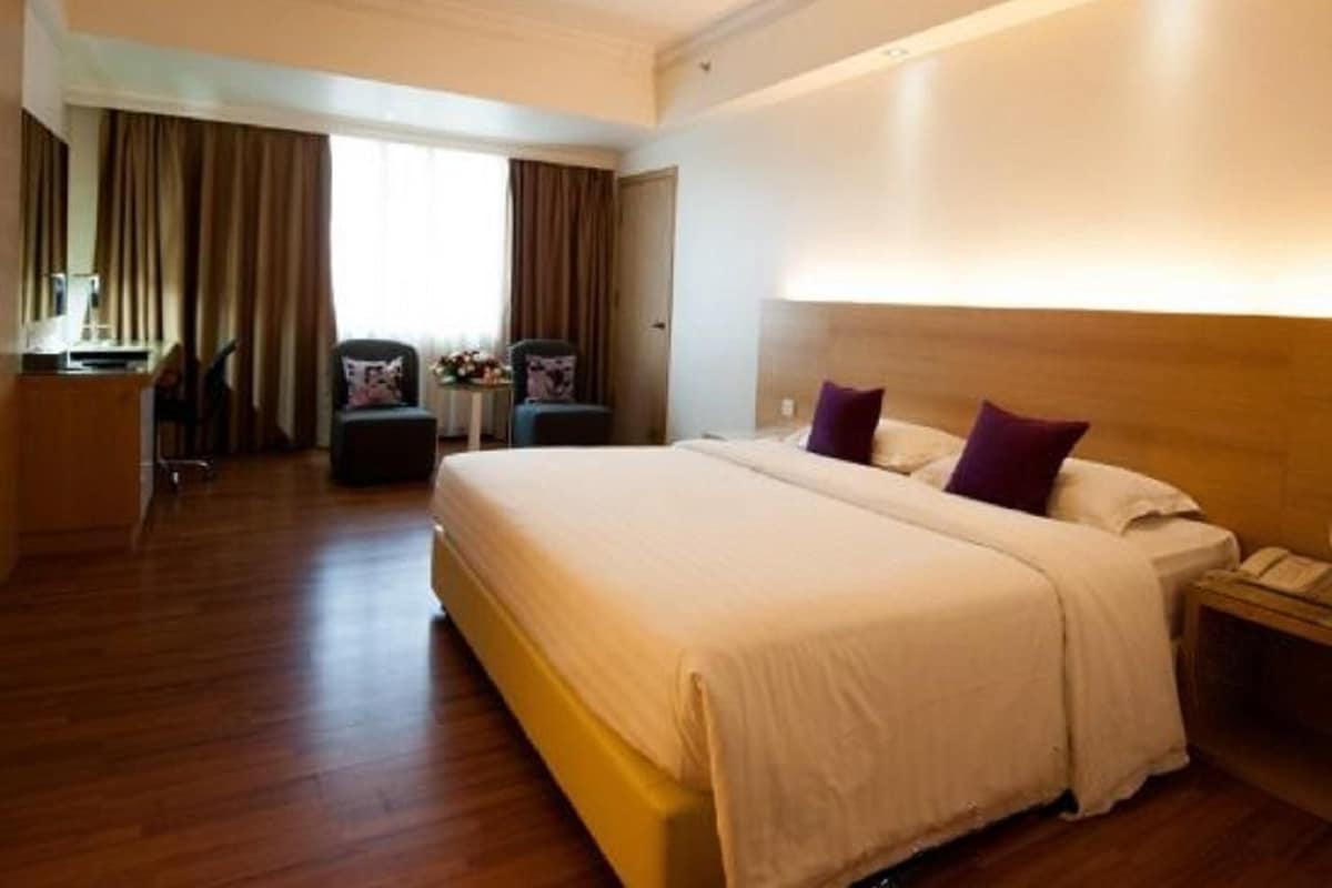 Une chambre d’hôtel avec un grand lit, une table de chevet, un bureau et une chaise.