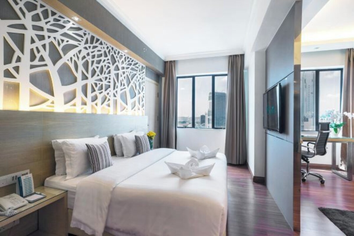Una habitación de hotel moderna con una cama grande, un escritorio con una silla, un televisor y un panel decorativo en la pared.