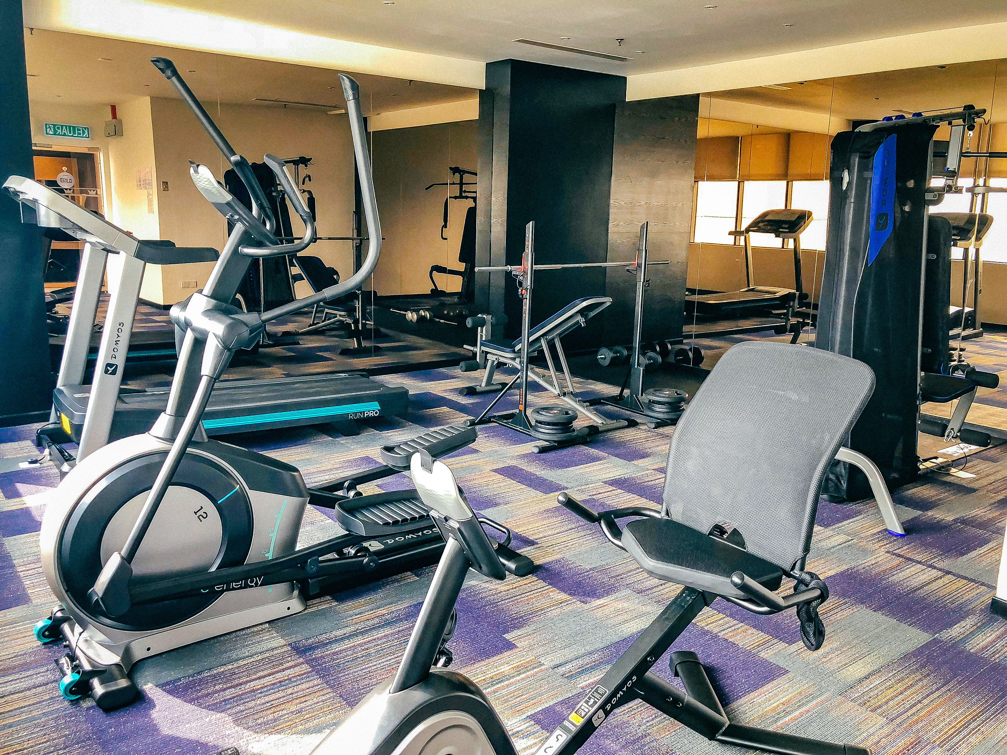 Un gimnasio con diversos equipos de ejercicio, incluyendo cintas de correr, bicicletas estáticas y máquinas de pesas.