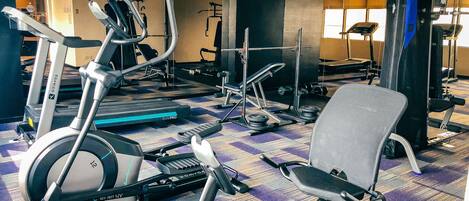 Un gimnasio con diversos equipos de ejercicio, incluyendo cintas de correr, bicicletas estáticas y máquinas de pesas.