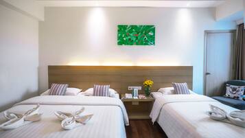 A hotel room with two beds, a nightstand with a lamp, a green abstract painting on the wall, and a door to the right.