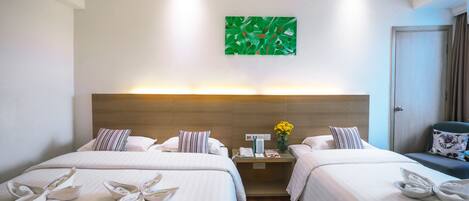 Habitación de hotel con dos camas, una mesita de noche con lámpara, un cuadro abstracto verde en la pared y una puerta a la derecha.