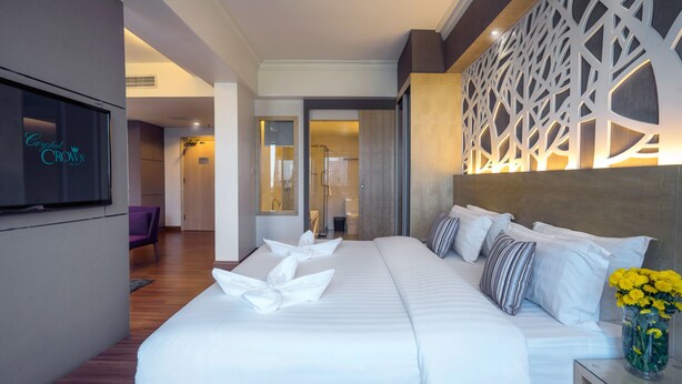 Habitación de hotel con una cama grande, un televisor montado en la pared y un panel decorativo.