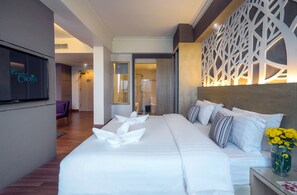 Une chambre d’hôtel avec un grand lit, un téléviseur fixé au mur et un panneau décoratif.