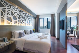 Una habitación de hotel moderna con una cama grande, un escritorio, un televisor y vistas a la ciudad.