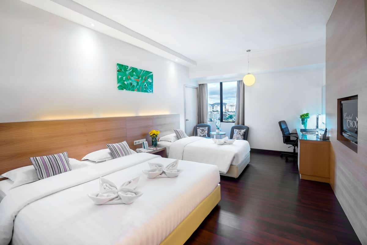 A hotel room with two beds, a desk, a chair, a TV, and a city view.
