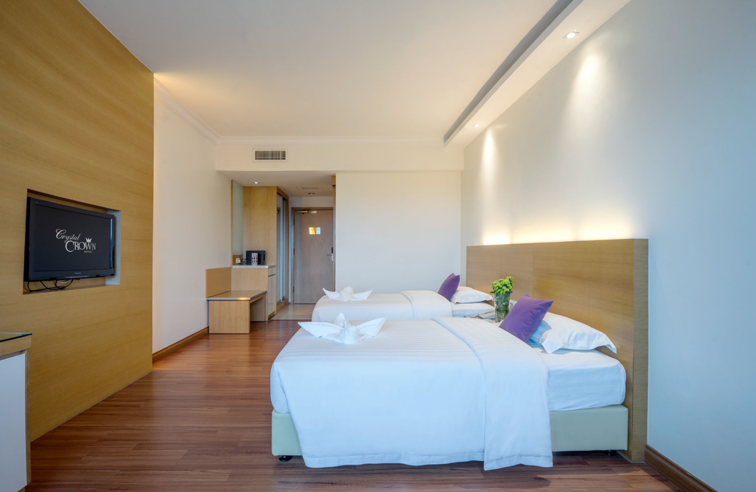 A hotel room with two beds, a TV, a desk, and a bathroom visible in the background.