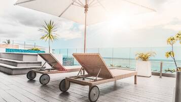 Una piscina al aire libre, sombrillas, sillones reclinables de piscina