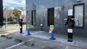 An EV charging station with a modern building in the background. - APA Hotel Kagoshima Kokubu (Kirishima)