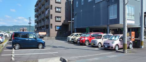 A parking lot with several cars parked in front of a building with multiple floors and balconies.