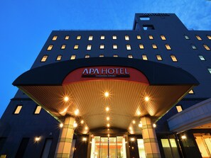 The APA HOTEL entrance with a modern design, featuring a prominent red and black sign, multiple illuminated windows, and a well-lit facade. - APA Hotel Kagoshima Kokubu (Kirishima)