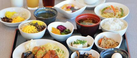 A variety of dishes and beverages on a tray, including noodles, rice, and a bowl of soup.