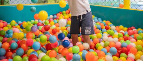 A child playing in a ball pit filled with multicolored balls.