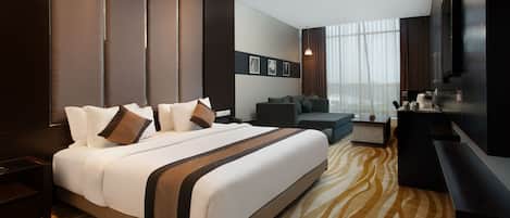 Una habitación de hotel moderna con una cama grande, un sofá, un escritorio y un televisor.