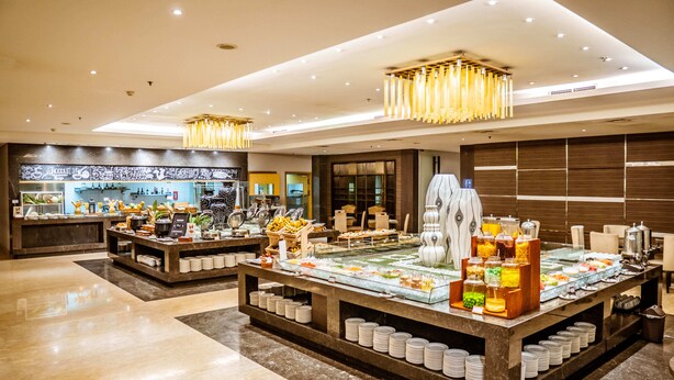 A modern hotel lobby with a buffet area, marble flooring, and contemporary lighting fixtures. - Grand Tjokro Premier Bandung (Bandung)