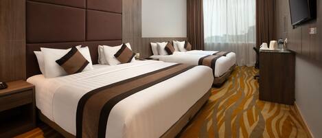 Une chambre d’hôtel avec deux lits, un téléviseur à écran plat, un minibar et une grande fenêtre avec des rideaux.