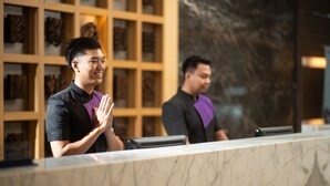 A reception desk with a marble top and a wooden panel background. - Grand Tjokro Premier Bandung (Bandung)