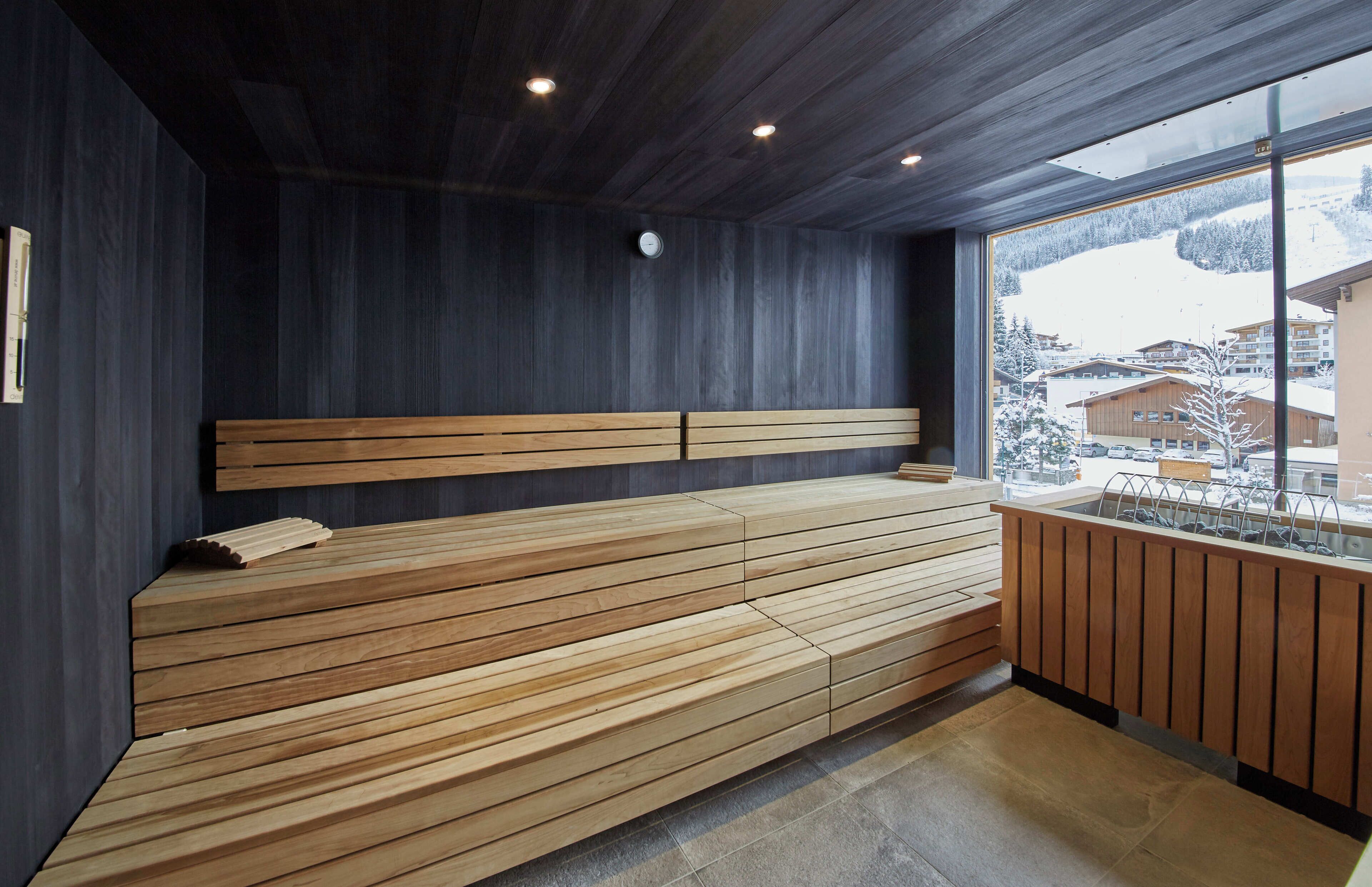Una sauna moderna con bancos de madera y un ventanal con vistas a un paisaje nevado.