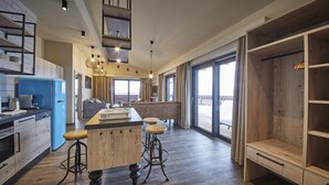 Cocina moderna con una isla central, taburetes de bar y vistas al exterior.